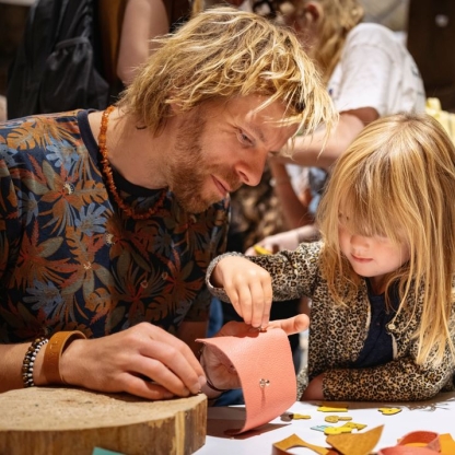 man en kind bezig met het maken van een portefeuille tijdens een atelier rond leerbewerking in Bokrijk